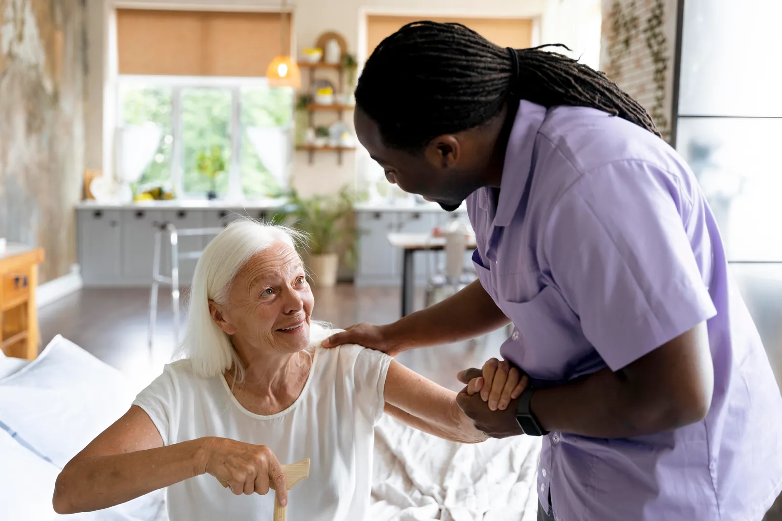 A Black male care worker supporting an older woman at home